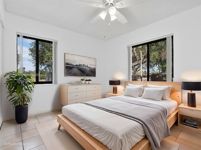 tiled bedroom with ceiling fan and multiple windows