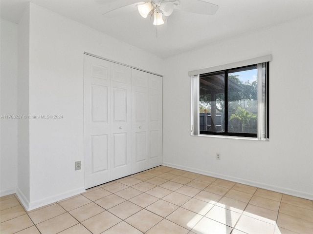 unfurnished bedroom featuring ceiling fan, a closet, and light tile patterned floors