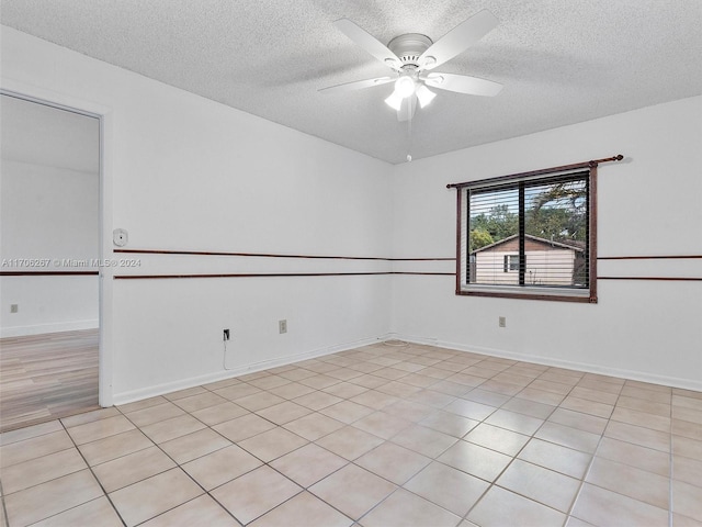 unfurnished room featuring ceiling fan, light tile patterned floors, and a textured ceiling