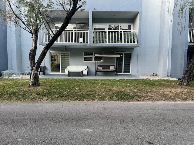 exterior space with ceiling fan, a yard, an outdoor living space, a balcony, and a patio