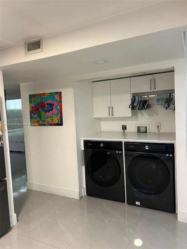 washroom with washer and dryer and cabinets