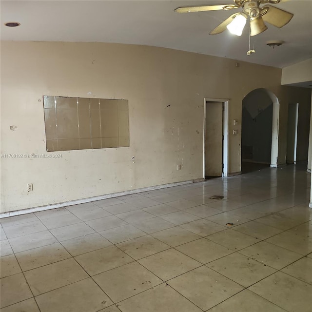 empty room featuring ceiling fan, light tile patterned floors, and vaulted ceiling