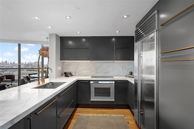 kitchen featuring decorative backsplash, modern cabinets, oven, a city view, and a sink