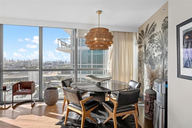 dining room with a wealth of natural light, a city view, a notable chandelier, and wood finished floors