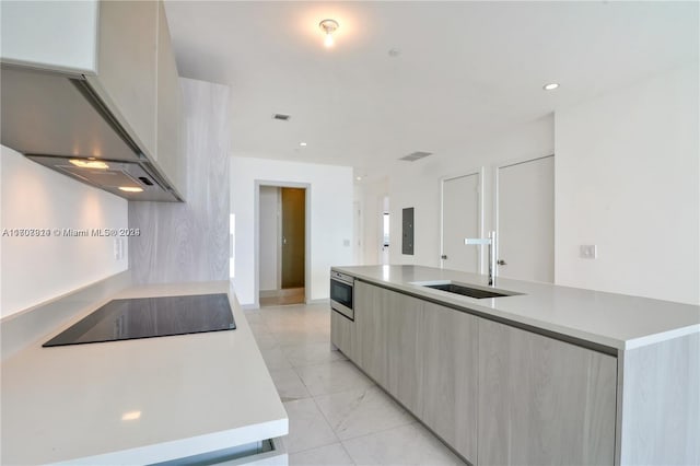 kitchen with black electric stovetop, wall chimney range hood, sink, a center island with sink, and electric panel