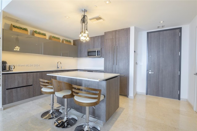 kitchen featuring pendant lighting, a center island, a kitchen breakfast bar, and sink