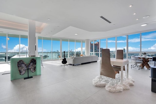 interior space featuring expansive windows, a water view, sink, and a tray ceiling