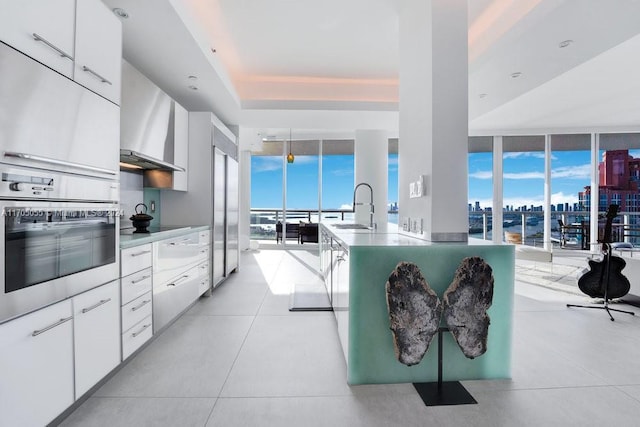 kitchen featuring stainless steel oven, white cabinets, plenty of natural light, and sink