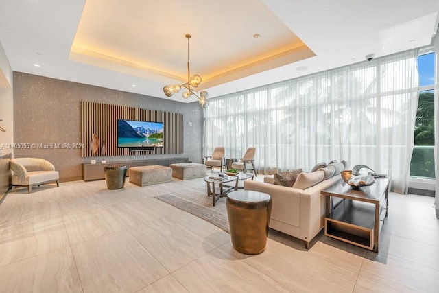 living room with a tray ceiling, an inviting chandelier, and floor to ceiling windows