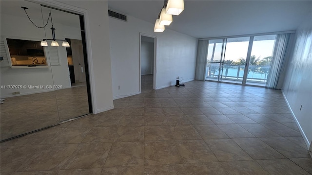 empty room with tile patterned flooring and expansive windows