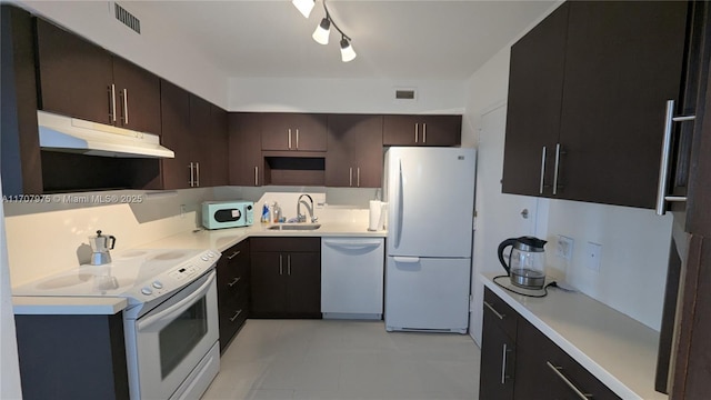 kitchen with dark brown cabinets, white appliances, and sink