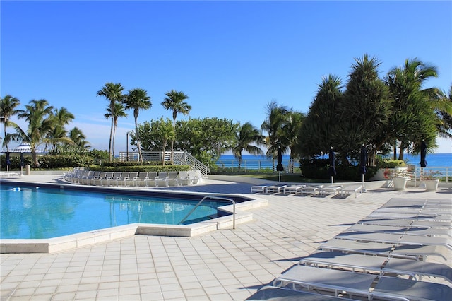 view of pool with a water view and a patio