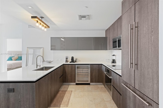 kitchen featuring kitchen peninsula, appliances with stainless steel finishes, dark brown cabinets, sink, and wine cooler