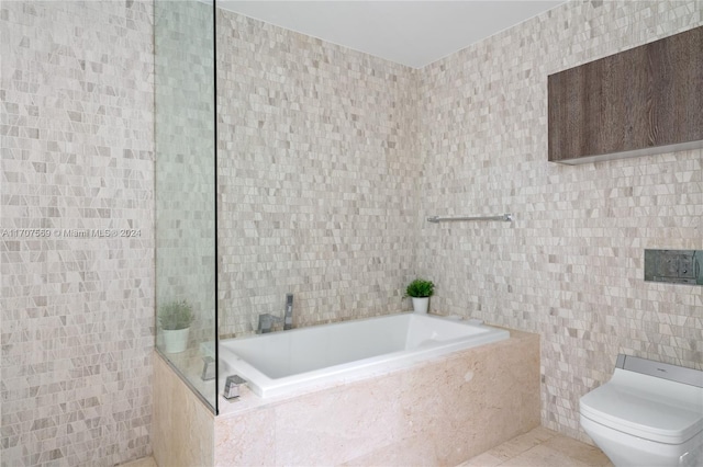 bathroom featuring tile patterned floors, toilet, tile walls, and tiled tub