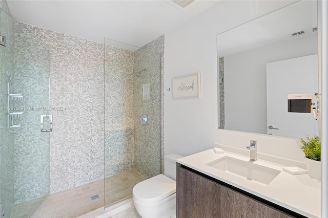 bathroom featuring tile patterned floors, vanity, toilet, and a shower with door