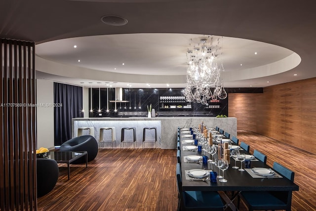 dining area with wood walls, hardwood / wood-style floors, and a chandelier