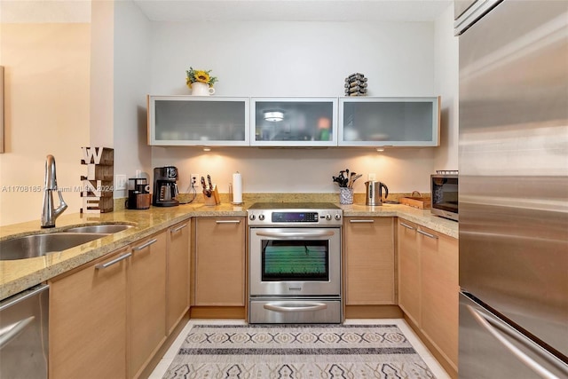 kitchen featuring light brown cabinets, sink, light stone countertops, kitchen peninsula, and stainless steel appliances