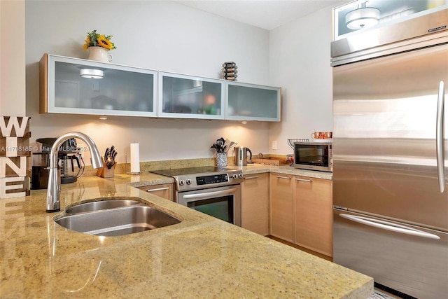 kitchen with light brown cabinetry, light stone counters, sink, and appliances with stainless steel finishes