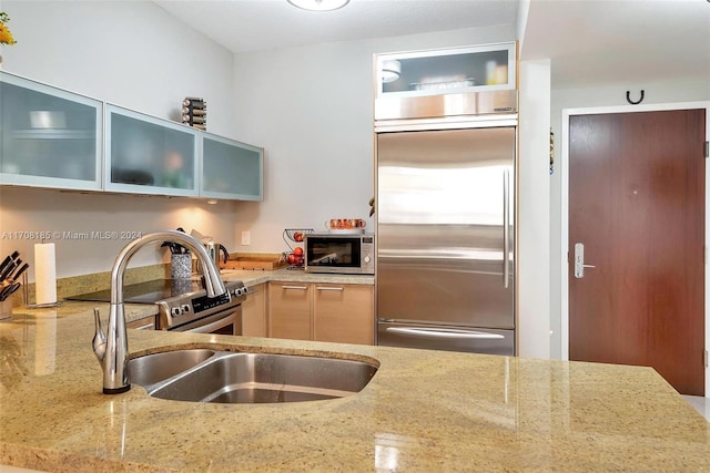 kitchen featuring light stone counters, sink, and appliances with stainless steel finishes