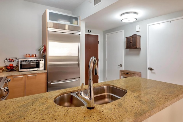 kitchen featuring kitchen peninsula, light stone countertops, sink, and appliances with stainless steel finishes