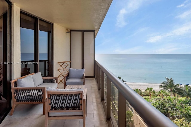 balcony featuring outdoor lounge area, a water view, and a view of the beach