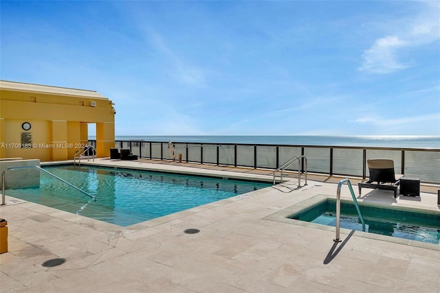 view of swimming pool with a beach view, a water view, a patio, and a hot tub