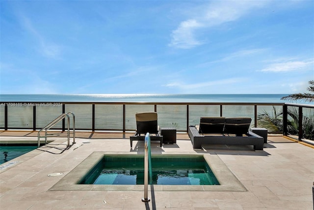 view of pool with an in ground hot tub, a water view, and a view of the beach