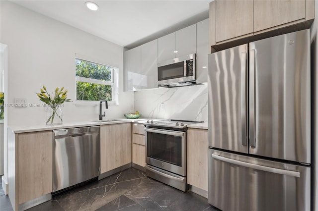 kitchen with light brown cabinets, backsplash, white cabinets, sink, and stainless steel appliances