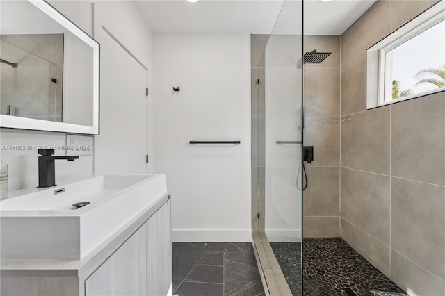 bathroom featuring a tile shower, vanity, and tile patterned floors