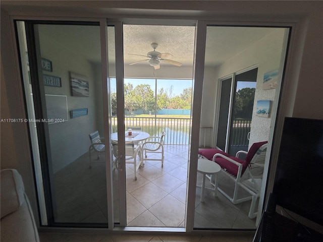 doorway to outside featuring ceiling fan, a water view, and a textured ceiling