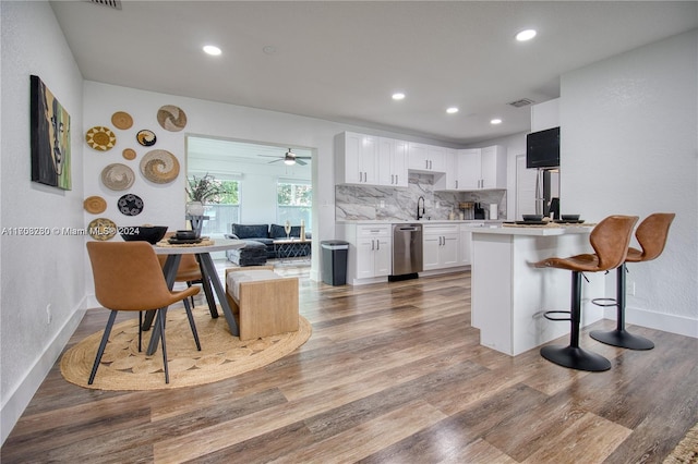 kitchen featuring backsplash, ceiling fan, dishwasher, white cabinets, and hardwood / wood-style floors