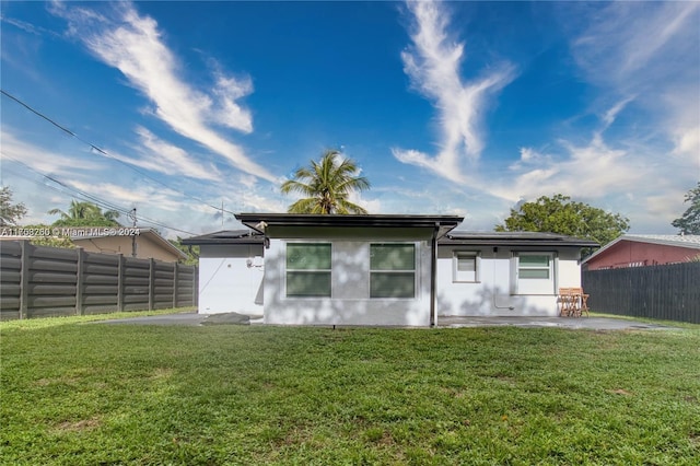 rear view of property with a patio and a lawn