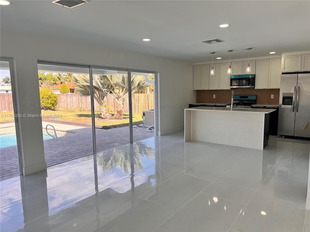 kitchen featuring light tile patterned flooring, an island with sink, pendant lighting, white cabinets, and appliances with stainless steel finishes