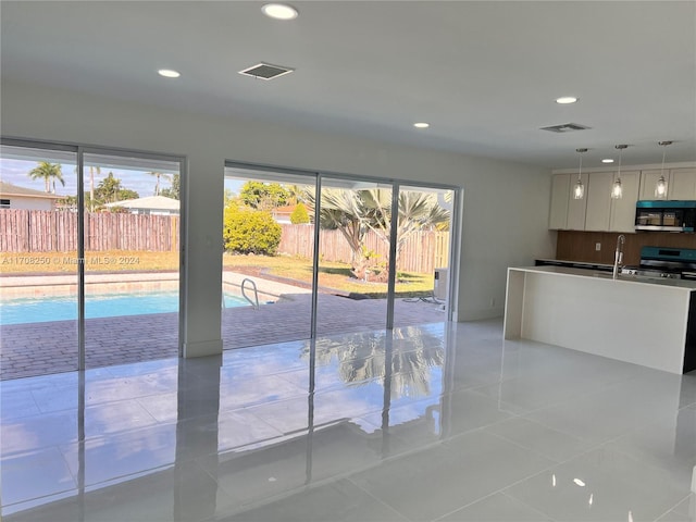 kitchen featuring white cabinetry, hanging light fixtures, light tile patterned flooring, and stainless steel appliances