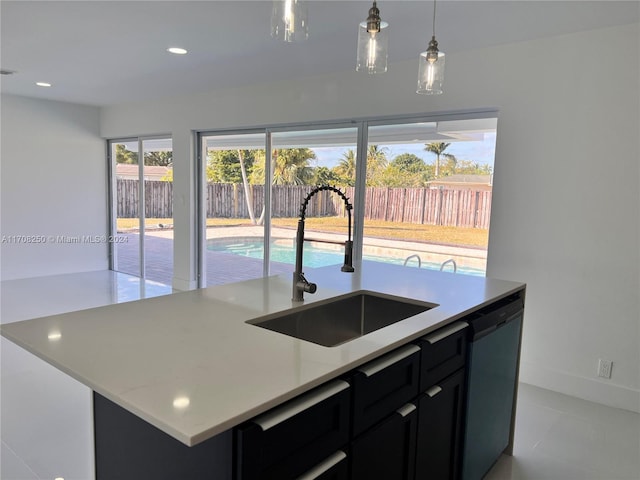 kitchen featuring a kitchen island with sink, sink, stainless steel dishwasher, light tile patterned floors, and decorative light fixtures