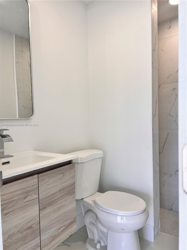 bathroom with tile patterned flooring, vanity, tiled shower, and toilet