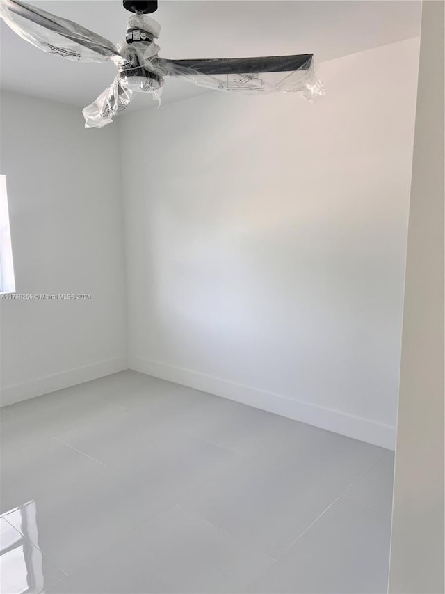 tiled empty room featuring ceiling fan