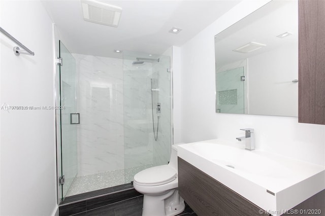 bathroom with an enclosed shower, vanity, and toilet