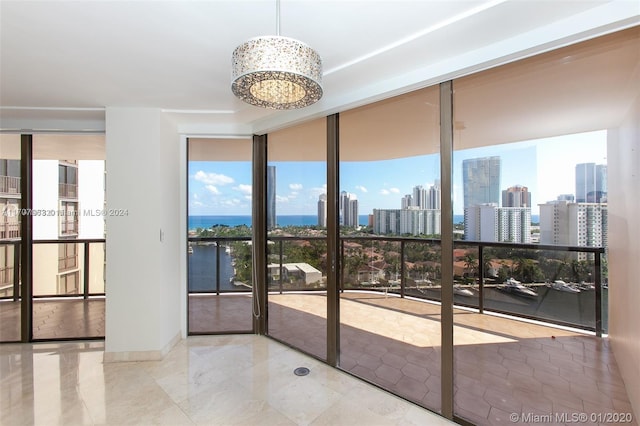 19667 Turnberry Way Unit 15A, Aventura, FL 33180 - tiled empty room featuring floor to ceiling windows, a chandelier, a skyline view, and a water view