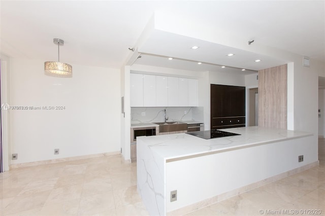 kitchen with white cabinetry, sink, light stone countertops, decorative light fixtures, and black electric cooktop