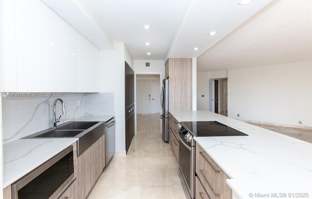 kitchen with sink, stainless steel appliances, tasteful backsplash, light stone counters, and light tile patterned floors