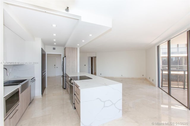 kitchen featuring a center island, light stone countertops, sink, and appliances with stainless steel finishes