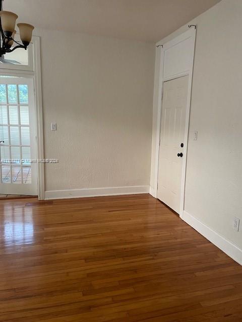 empty room with dark wood-type flooring and a chandelier