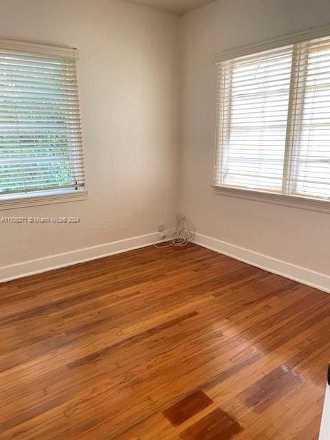 empty room with hardwood / wood-style flooring and a wealth of natural light