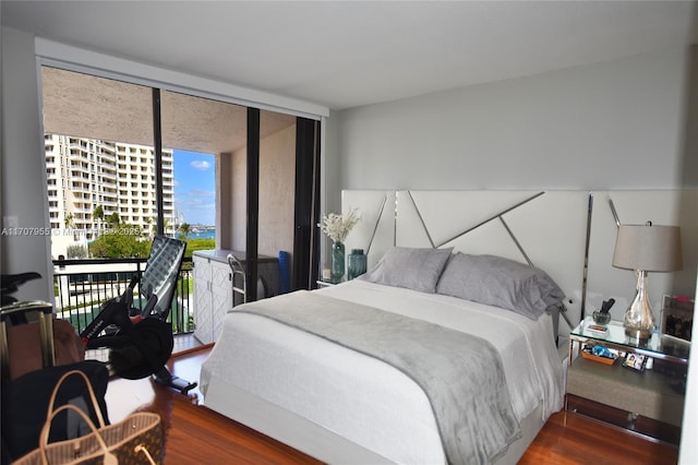 bedroom featuring dark wood-type flooring, a wall of windows, and access to outside