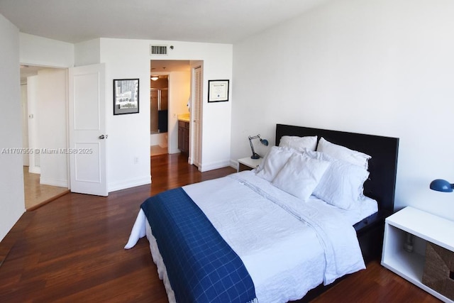 bedroom featuring ensuite bathroom and dark hardwood / wood-style flooring