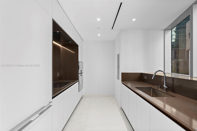 kitchen featuring oven, sink, black electric stovetop, and white cabinets