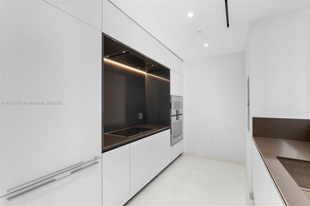 kitchen featuring black electric stovetop, oven, and white cabinets