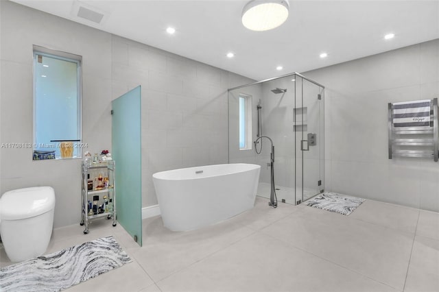 bathroom with radiator, tile patterned flooring, tile walls, and shower with separate bathtub