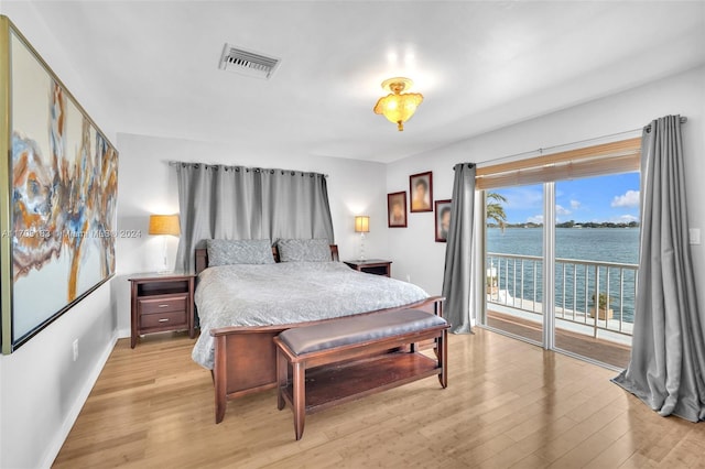 bedroom with access to exterior, light hardwood / wood-style floors, and a water view